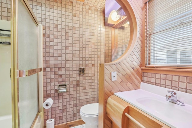 full bathroom with toilet, a shower with door, tile walls, and vanity