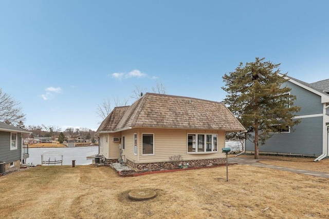 rear view of house with a shingled roof, mansard roof, and a yard