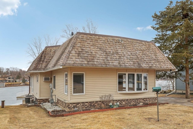 rear view of house featuring a shingled roof, a lawn, mansard roof, and central air condition unit