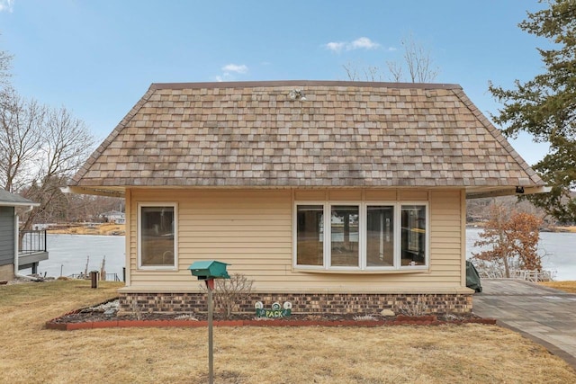 rear view of house with a shingled roof, a yard, and mansard roof