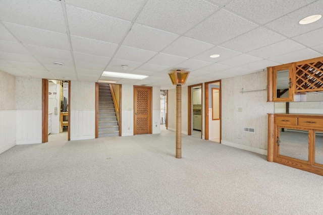 finished basement with carpet floors, visible vents, stairway, and wainscoting