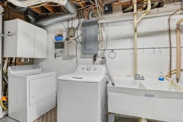 clothes washing area with a sink, cabinet space, electric panel, and washer and dryer