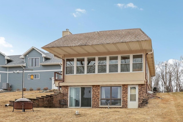 back of property with a shingled roof, stairs, central AC, and brick siding