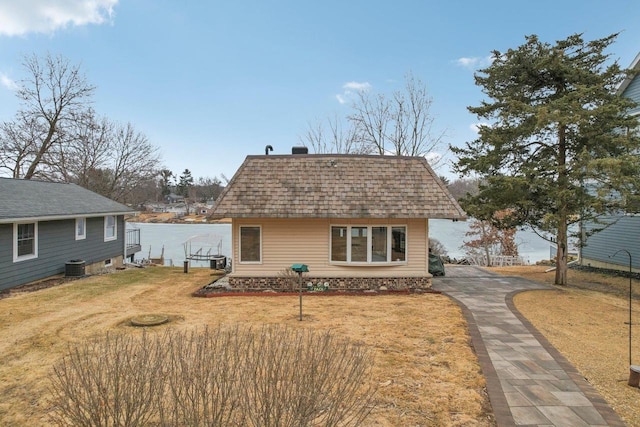 back of property featuring a yard, central AC unit, and roof with shingles