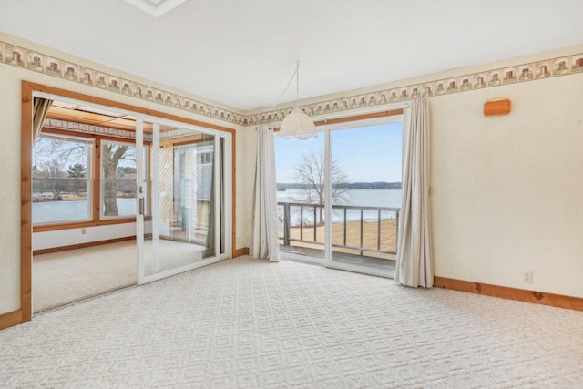 spare room featuring carpet floors, a water view, and baseboards