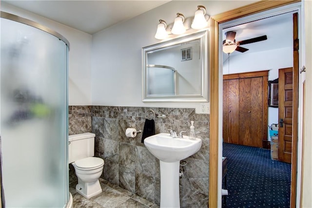 bathroom featuring a stall shower, visible vents, tile walls, and toilet