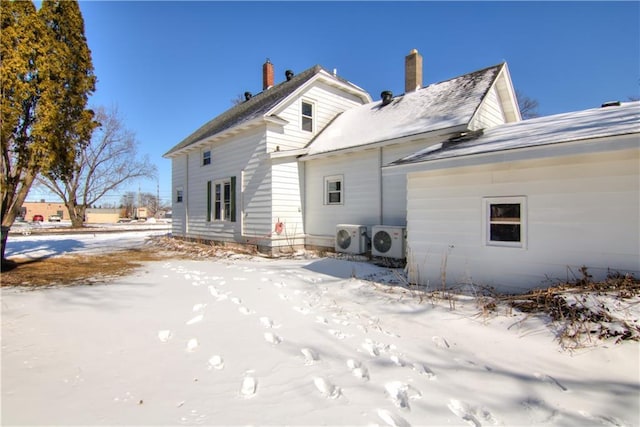 snow covered back of property featuring ac unit