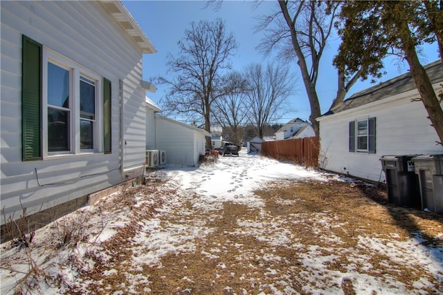 view of snow covered exterior with ac unit and fence