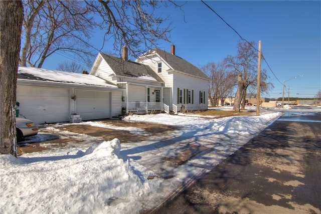 cape cod home with covered porch and an attached garage