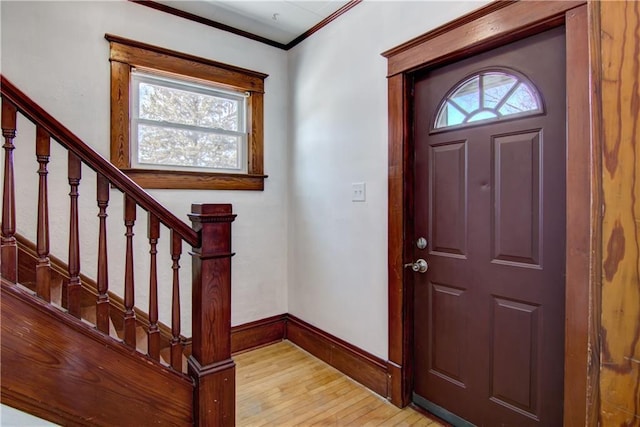 entryway featuring light wood-style floors, a wealth of natural light, crown molding, and baseboards