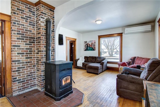 living area with a wood stove, wood-type flooring, arched walkways, and an AC wall unit