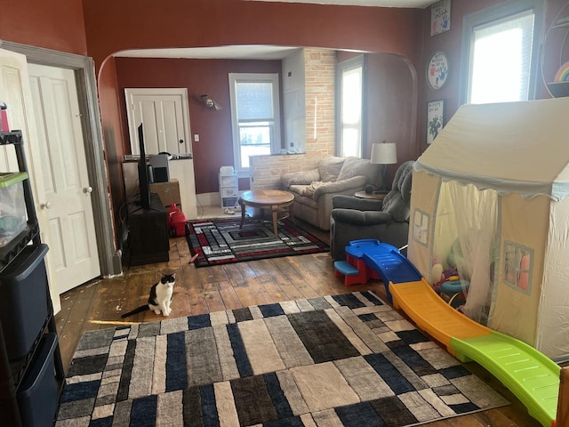 living area with arched walkways and wood-type flooring