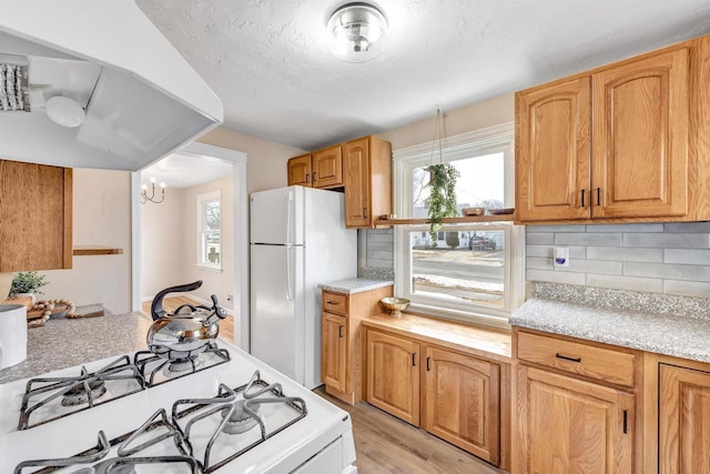 kitchen featuring light wood-style floors, white appliances, light countertops, and backsplash