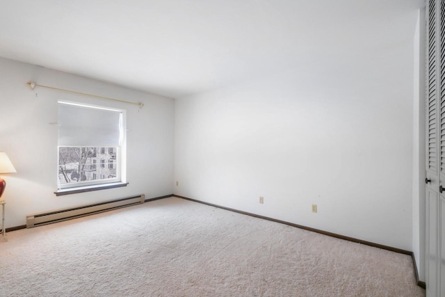 carpeted empty room featuring a baseboard heating unit and baseboards