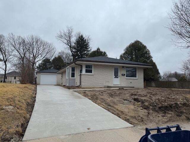 ranch-style house with an outbuilding, brick siding, a detached garage, fence, and concrete driveway