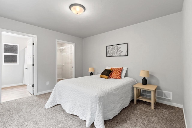 bedroom featuring carpet floors, visible vents, baseboards, and ensuite bathroom