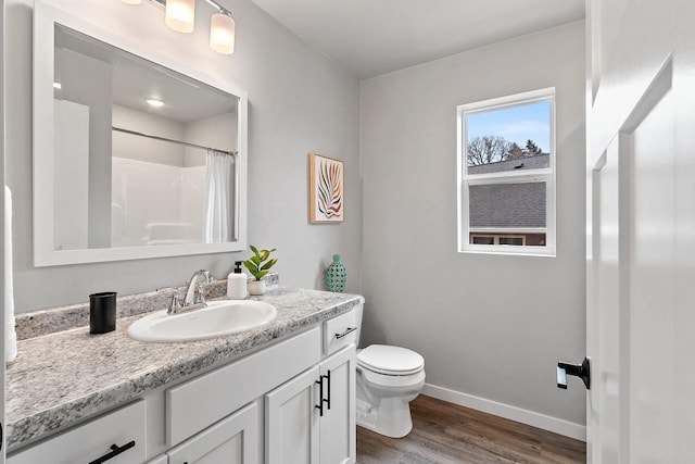 bathroom featuring a shower with shower curtain, toilet, vanity, wood finished floors, and baseboards