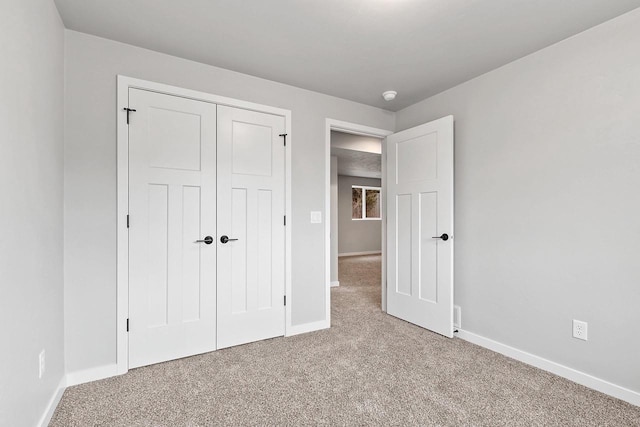 unfurnished bedroom featuring carpet floors, a closet, and baseboards