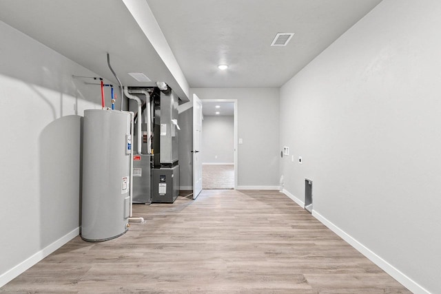 utility room featuring heating unit, visible vents, and electric water heater