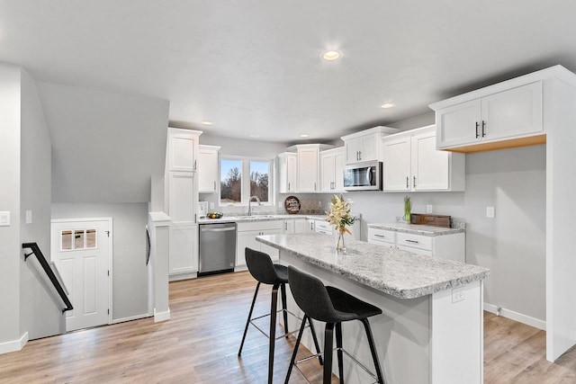 kitchen featuring light wood finished floors, appliances with stainless steel finishes, a sink, and recessed lighting