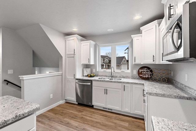 kitchen featuring light wood-style flooring, recessed lighting, stainless steel appliances, a sink, and white cabinets