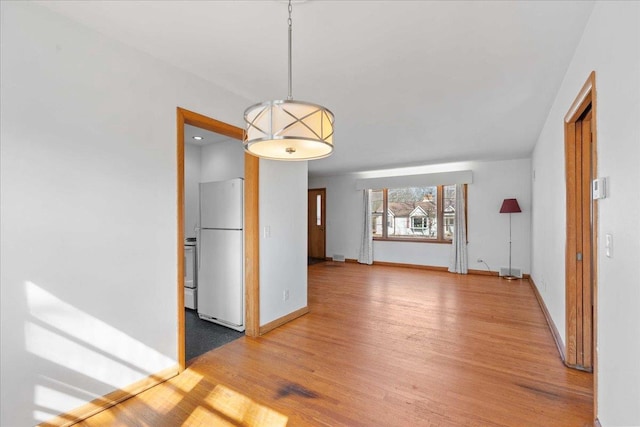 unfurnished dining area with light wood-type flooring and baseboards