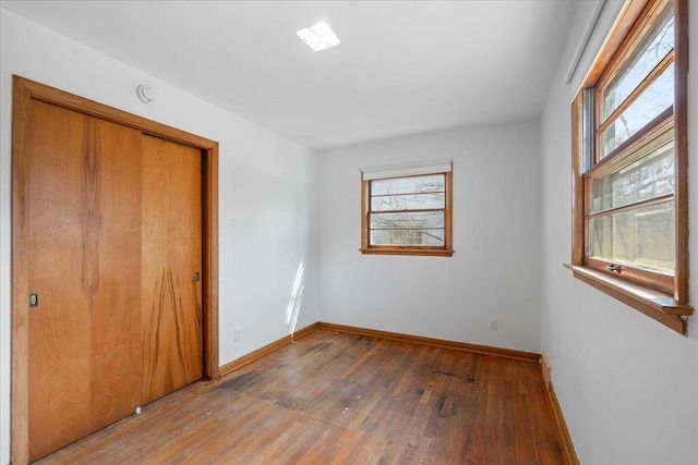 unfurnished bedroom with light wood-style flooring, baseboards, and a closet