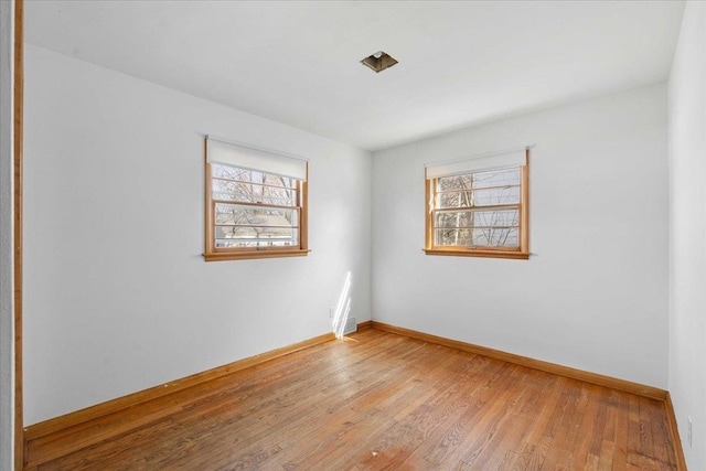 unfurnished room with plenty of natural light, light wood-style floors, and baseboards