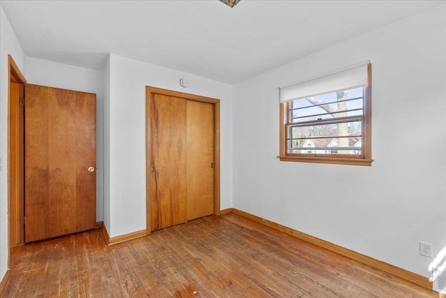 unfurnished bedroom with hardwood / wood-style floors, baseboards, and a closet