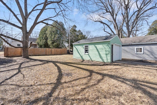 view of yard with driveway, a detached garage, an outdoor structure, and fence