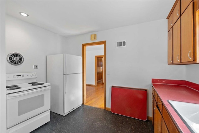 kitchen featuring a sink, visible vents, white appliances, and brown cabinetry