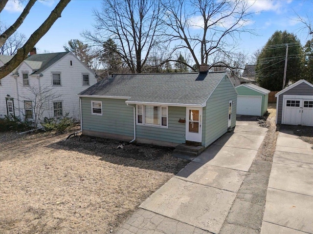 view of front of home featuring a garage, an outbuilding, a chimney, and a shingled roof