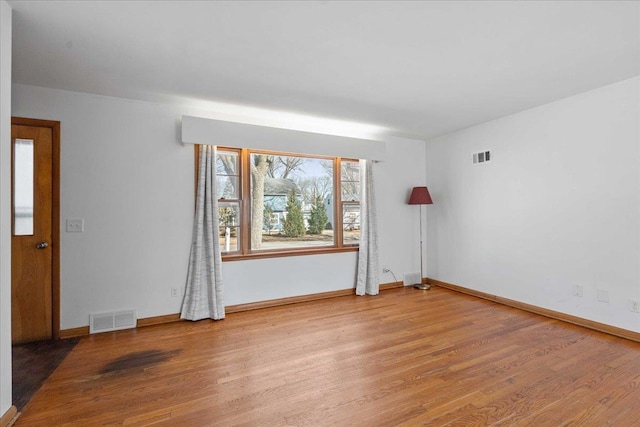 spare room featuring light wood-style flooring, baseboards, and visible vents