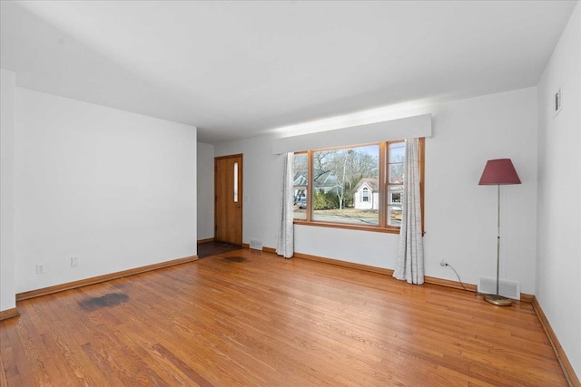 unfurnished room with light wood-type flooring, visible vents, and baseboards