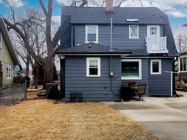 back of house with a shingled roof, fence, a yard, a chimney, and a patio area