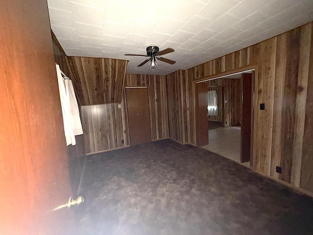 unfurnished room featuring wood walls and a ceiling fan