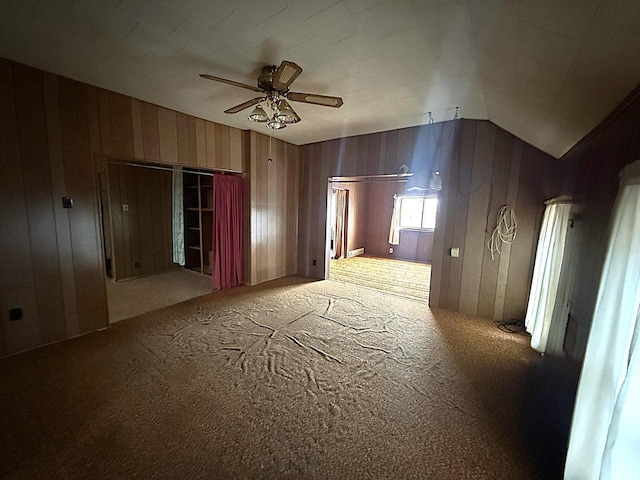 spare room with a ceiling fan, carpet, and wood walls