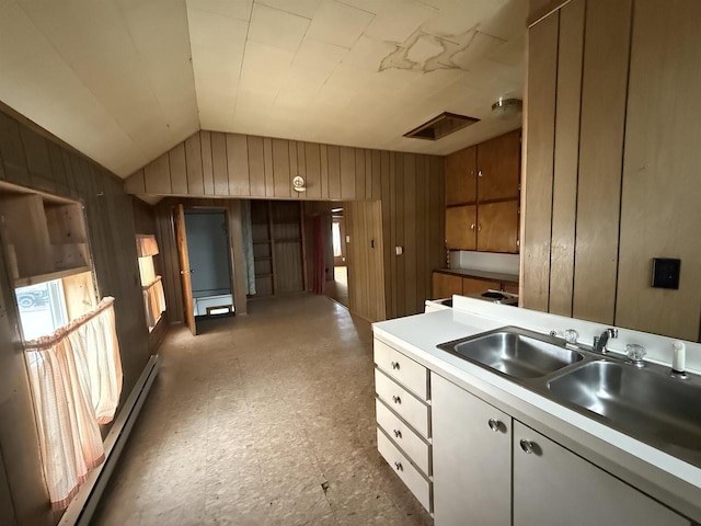 kitchen featuring light floors, a baseboard radiator, a sink, and wood walls