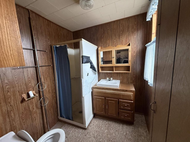 full bath with a stall shower, wooden walls, and vanity