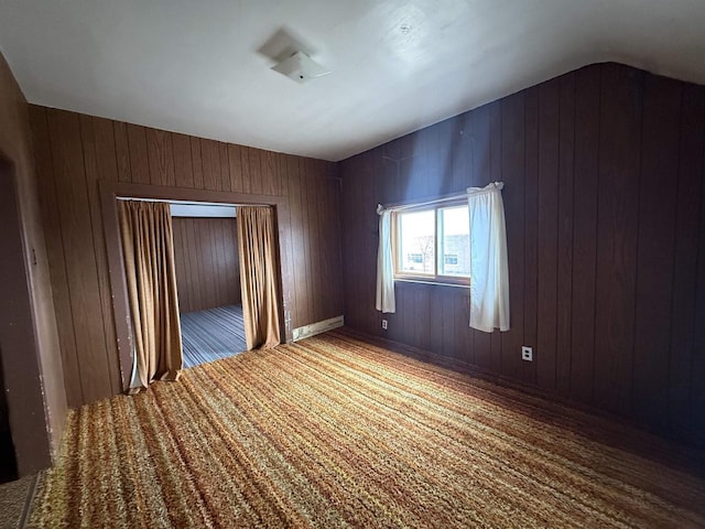 carpeted empty room with wood walls