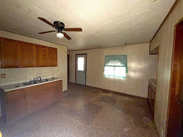 kitchen with dark floors, brown cabinets, light countertops, a ceiling fan, and a sink