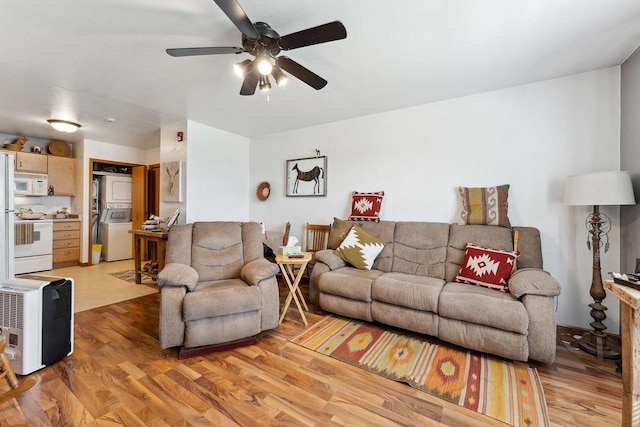 living room featuring light wood-type flooring, stacked washing maching and dryer, and ceiling fan