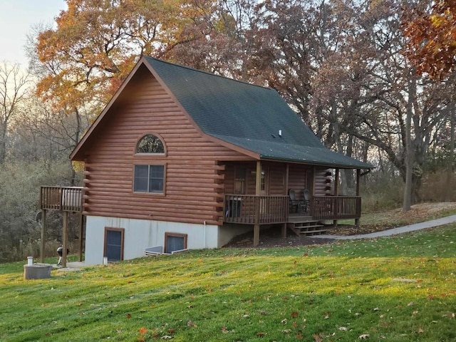 back of house with log exterior, a lawn, and a wooden deck