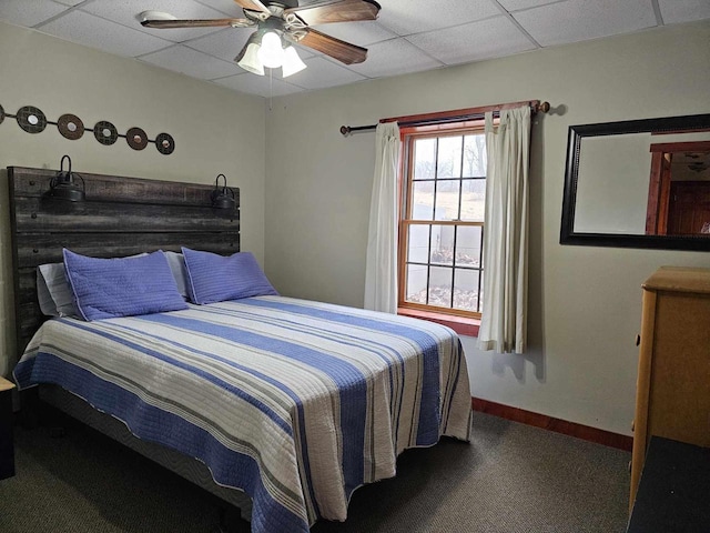 bedroom featuring a ceiling fan, baseboards, and a drop ceiling