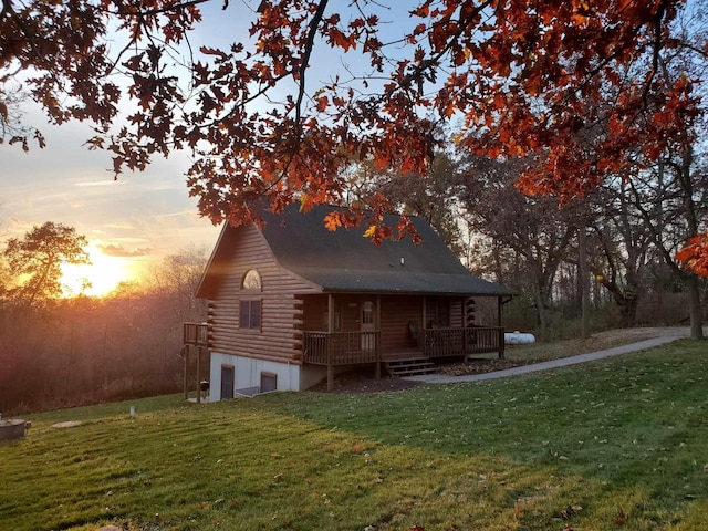 rear view of house featuring log exterior and a yard