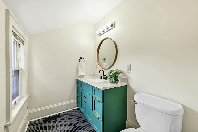 half bath featuring baseboards, toilet, and vanity