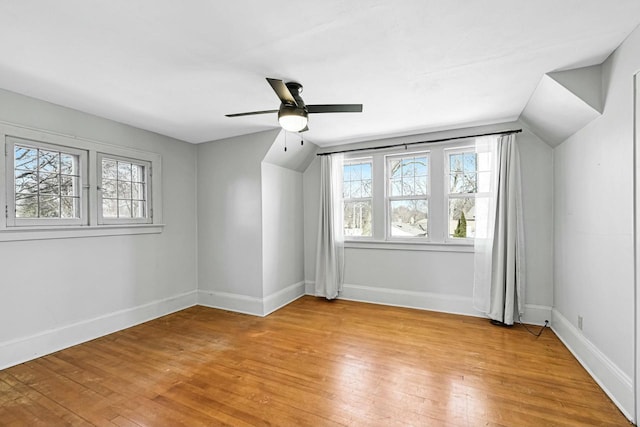 additional living space with vaulted ceiling, light wood-style floors, baseboards, and ceiling fan