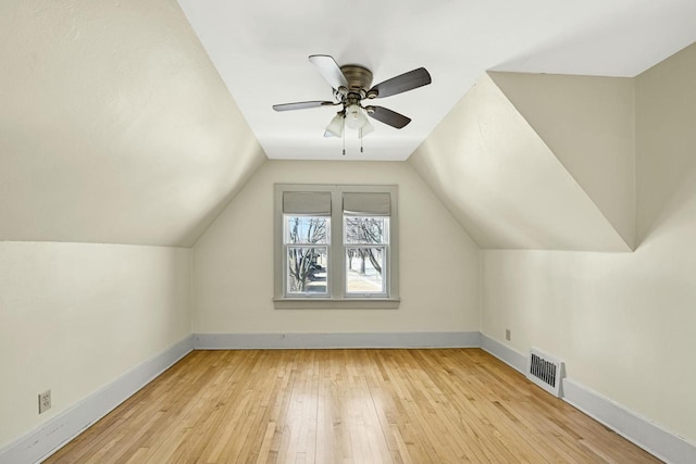 additional living space with visible vents, ceiling fan, baseboards, vaulted ceiling, and hardwood / wood-style floors