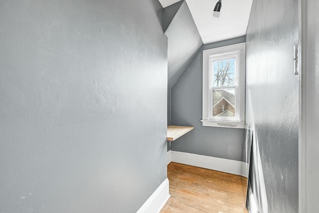 staircase featuring baseboards, hardwood / wood-style floors, and vaulted ceiling