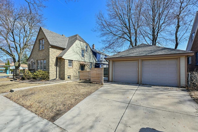 view of front of property featuring an outdoor structure, brick siding, a detached garage, and a shingled roof